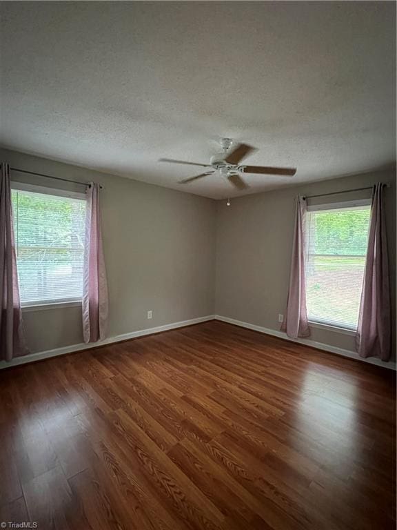 spare room featuring plenty of natural light, a textured ceiling, ceiling fan, and wood finished floors