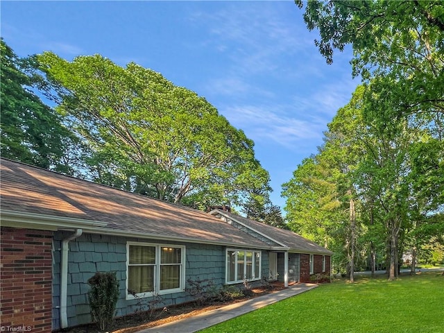 view of side of home with a lawn and a shingled roof