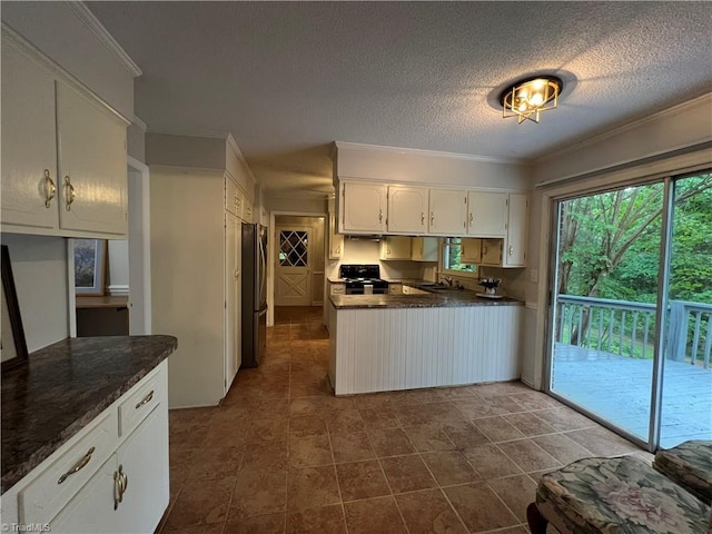 kitchen featuring crown molding, freestanding refrigerator, a peninsula, black electric range oven, and white cabinets