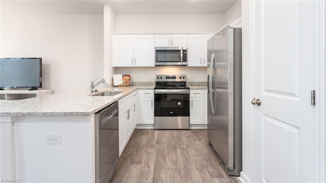 kitchen with white cabinets, stainless steel appliances, light stone countertops, and sink