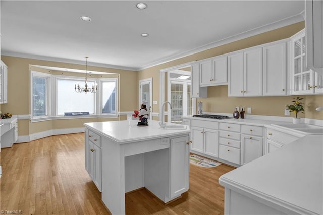 kitchen featuring white cabinetry, a kitchen island, pendant lighting, light wood-type flooring, and sink