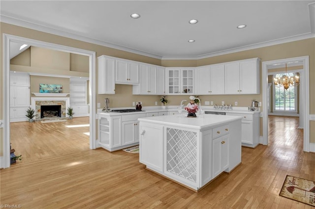 kitchen featuring white cabinetry, a kitchen island, a high end fireplace, light hardwood / wood-style flooring, and a chandelier