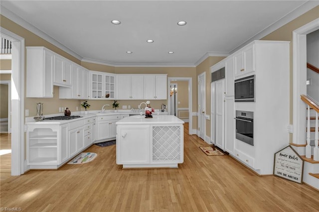 kitchen with white cabinets, appliances with stainless steel finishes, light hardwood / wood-style floors, and a kitchen island