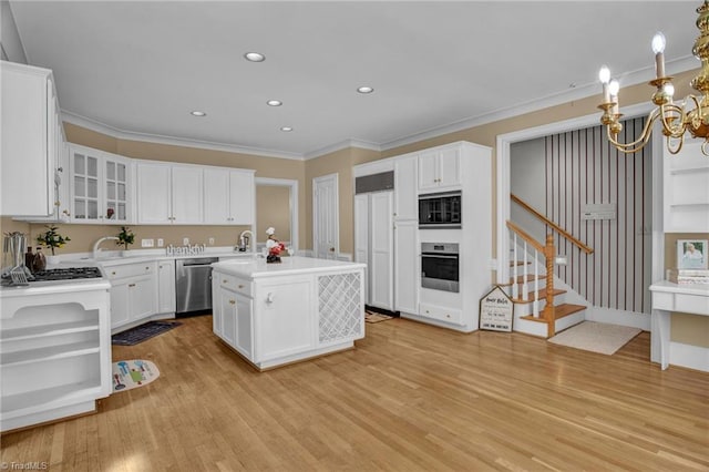 kitchen featuring appliances with stainless steel finishes, white cabinets, a kitchen island with sink, light hardwood / wood-style flooring, and ornamental molding