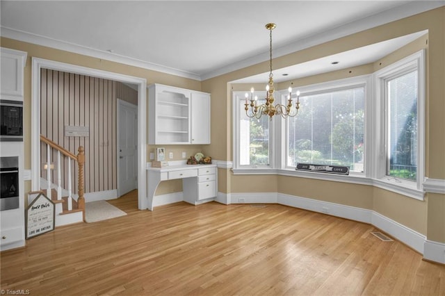 unfurnished dining area with light hardwood / wood-style flooring, crown molding, and a chandelier