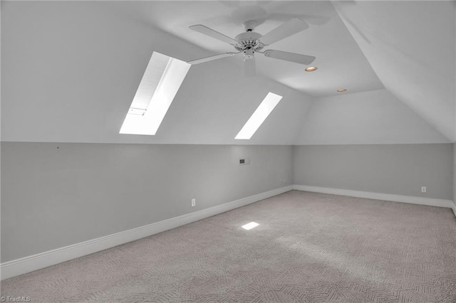 additional living space with lofted ceiling with skylight, light carpet, and ceiling fan