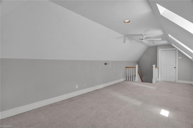 additional living space featuring carpet floors, vaulted ceiling with skylight, and ceiling fan