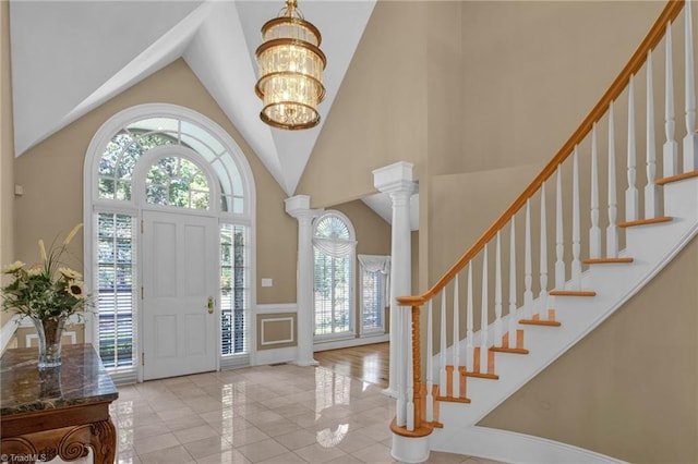 foyer with a high ceiling, a chandelier, and decorative columns