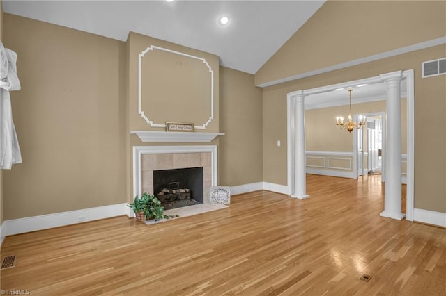 unfurnished living room with a chandelier, high vaulted ceiling, a tile fireplace, light wood-type flooring, and crown molding