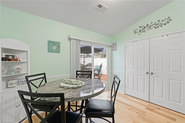 dining room featuring lofted ceiling, built in features, and light hardwood / wood-style flooring