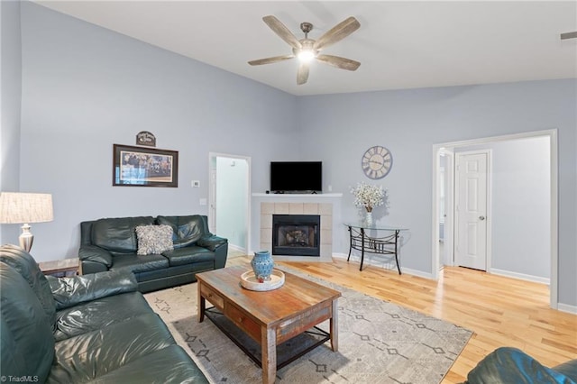 living room featuring a tile fireplace, ceiling fan, vaulted ceiling, and hardwood / wood-style floors