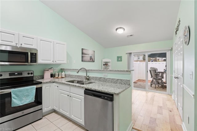 kitchen featuring stainless steel appliances, white cabinetry, sink, and light stone counters