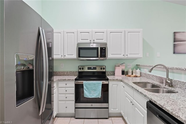 kitchen featuring sink, white cabinets, light tile patterned floors, light stone countertops, and appliances with stainless steel finishes