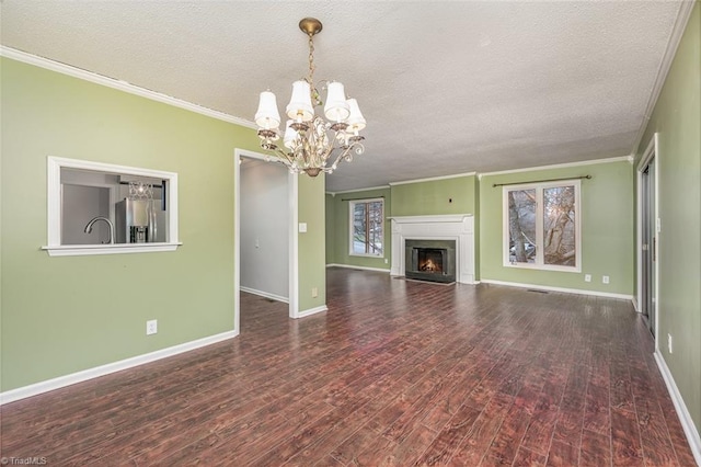 unfurnished living room featuring ornamental molding, dark hardwood / wood-style floors, a chandelier, and a textured ceiling