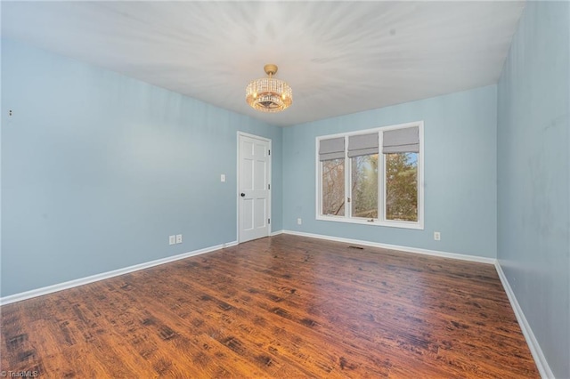 spare room featuring dark hardwood / wood-style flooring and an inviting chandelier