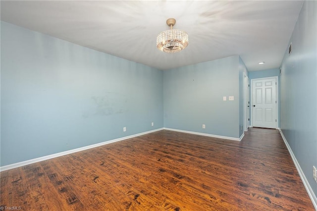 spare room featuring dark hardwood / wood-style floors and a chandelier