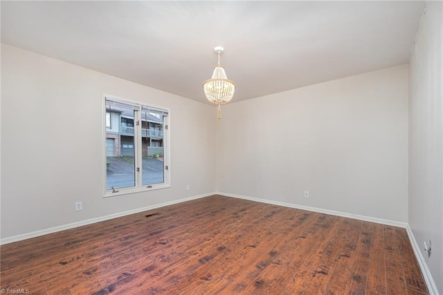 unfurnished room with dark hardwood / wood-style floors and a notable chandelier