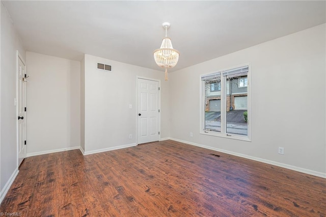 empty room with an inviting chandelier and dark wood-type flooring