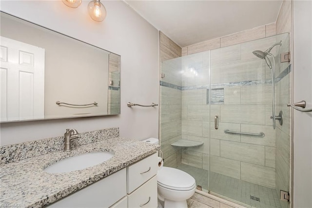 bathroom with toilet, vanity, and a shower with shower door