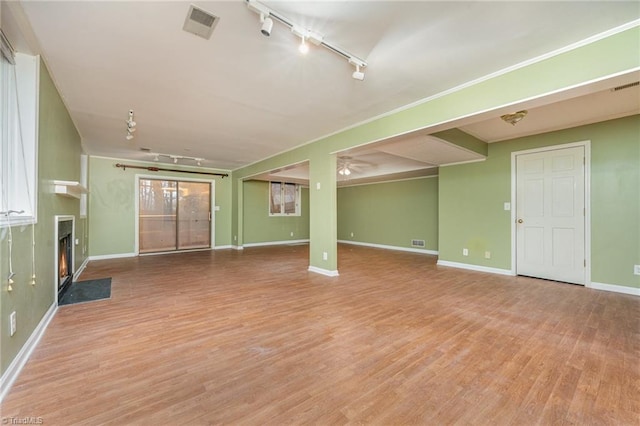 unfurnished living room featuring track lighting and light hardwood / wood-style floors