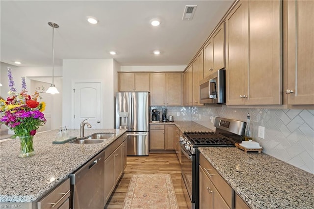 4077 Glenn Knoll Ln, Winston-Salem, NC 27107 - kitchen with stainless steel appliances, light wood finished floors, a sink, light stone counters, and backsplash