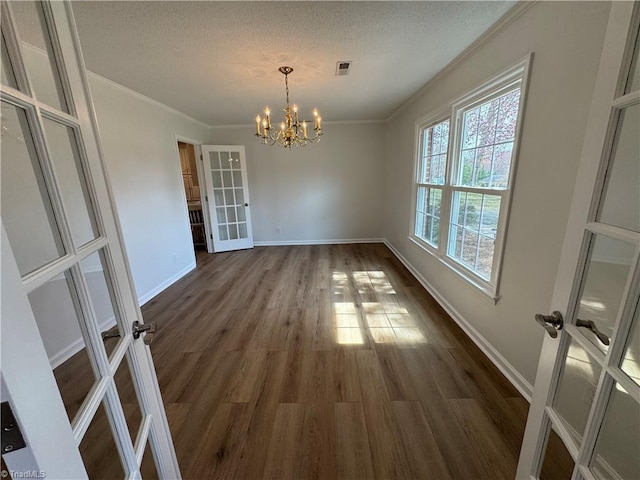 unfurnished dining area with visible vents, dark wood-style flooring, french doors, crown molding, and a notable chandelier