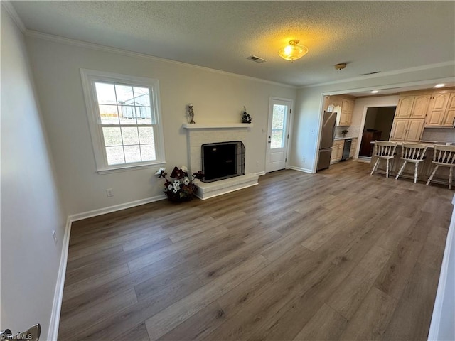 living room with crown molding, plenty of natural light, a fireplace, and visible vents