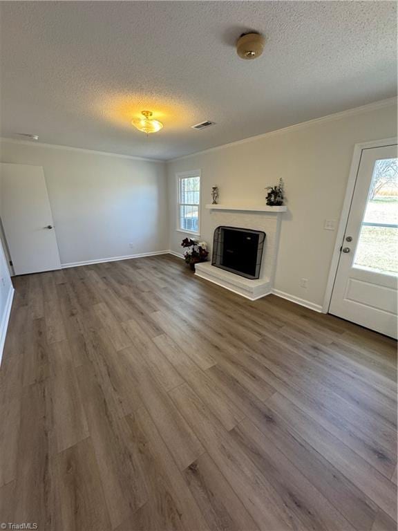 unfurnished living room with a textured ceiling, a fireplace with raised hearth, and wood finished floors