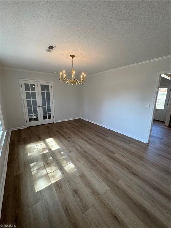 spare room with french doors, a textured ceiling, dark wood-type flooring, and an inviting chandelier