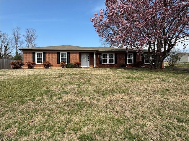 ranch-style home featuring brick siding, a front yard, and fence