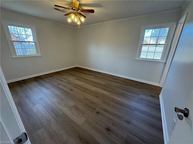 spare room featuring visible vents, a healthy amount of sunlight, dark wood finished floors, and crown molding