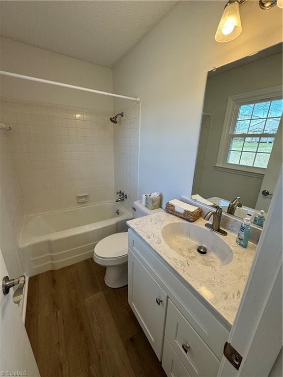 bathroom with toilet, shower / tub combination, vanity, wood finished floors, and a textured ceiling