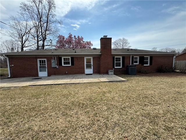 rear view of property with a patio, central AC, a yard, brick siding, and a chimney