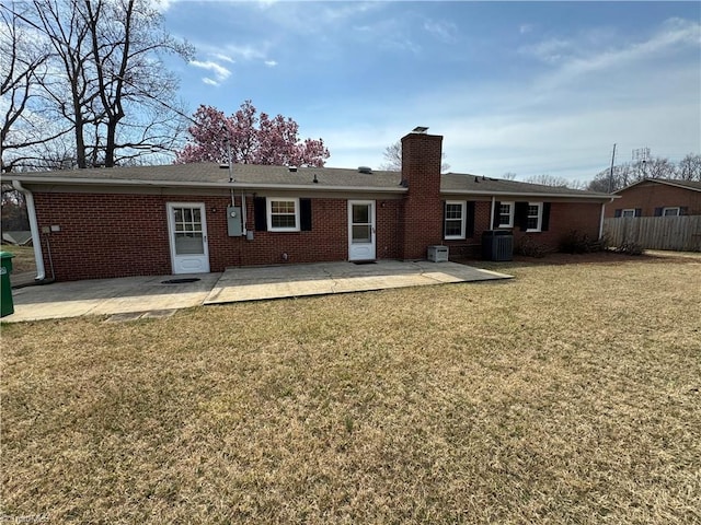 back of house with brick siding, fence, a chimney, a yard, and a patio area