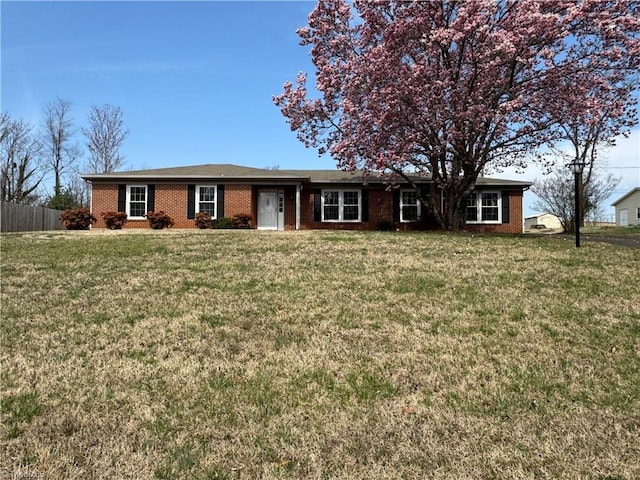 ranch-style house featuring brick siding, a front lawn, and fence