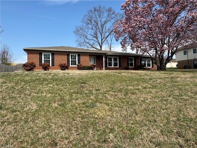 ranch-style home with brick siding, a front lawn, and fence