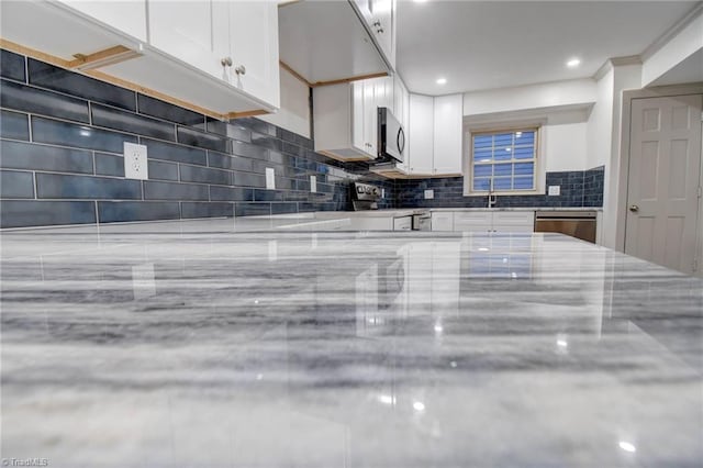 kitchen with white cabinetry, decorative backsplash, sink, and stainless steel appliances