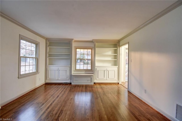 unfurnished living room featuring built in shelves, hardwood / wood-style floors, a healthy amount of sunlight, and ornamental molding