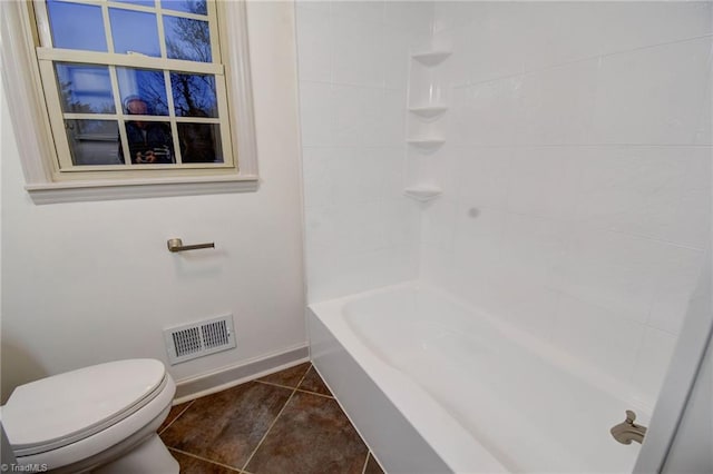 bathroom featuring tile patterned floors, tiled shower / bath combo, and toilet