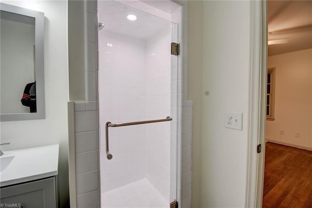 bathroom with hardwood / wood-style floors, vanity, and a shower with shower door