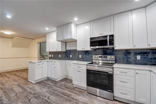 kitchen with kitchen peninsula, appliances with stainless steel finishes, tasteful backsplash, light hardwood / wood-style flooring, and white cabinets