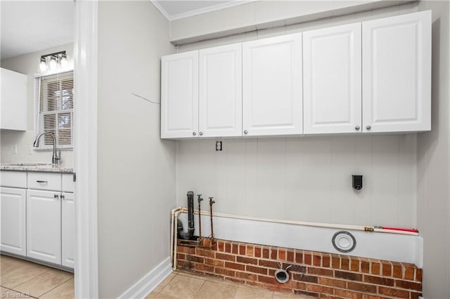 clothes washing area with light tile patterned floors, ornamental molding, and a sink