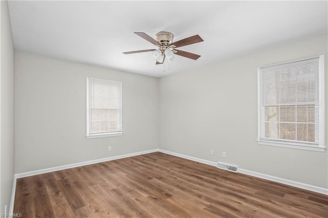 unfurnished room featuring baseboards, visible vents, ceiling fan, and wood finished floors