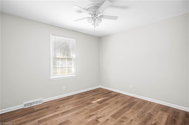 spare room with ceiling fan, wood finished floors, visible vents, and baseboards