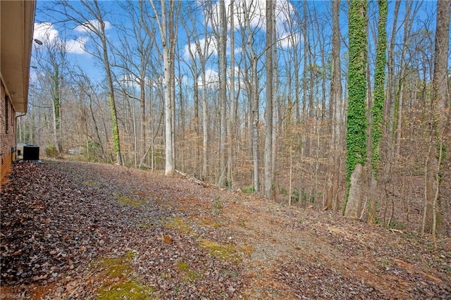 view of yard with a view of trees and central air condition unit