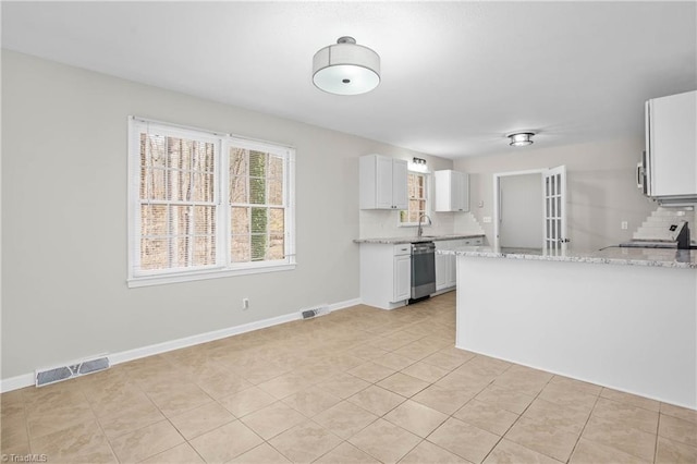 kitchen with baseboards, visible vents, dishwasher, backsplash, and a sink