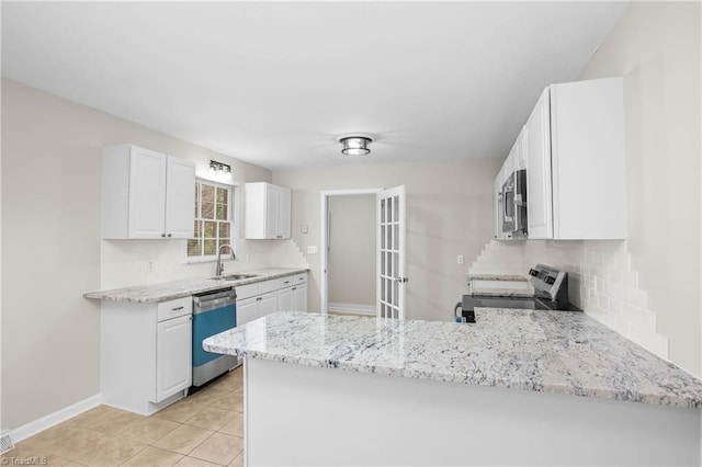 kitchen featuring light stone counters, a peninsula, a sink, white cabinetry, and appliances with stainless steel finishes