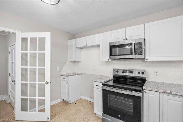 kitchen featuring light stone counters, stainless steel appliances, decorative backsplash, white cabinetry, and light tile patterned flooring