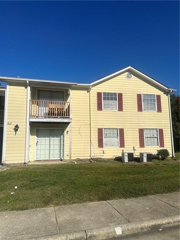 view of front facade with central AC, a balcony, and a front lawn