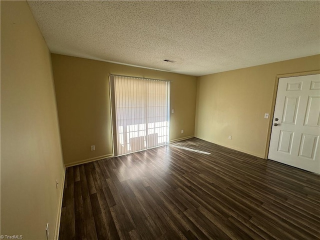 empty room featuring a textured ceiling and dark hardwood / wood-style flooring